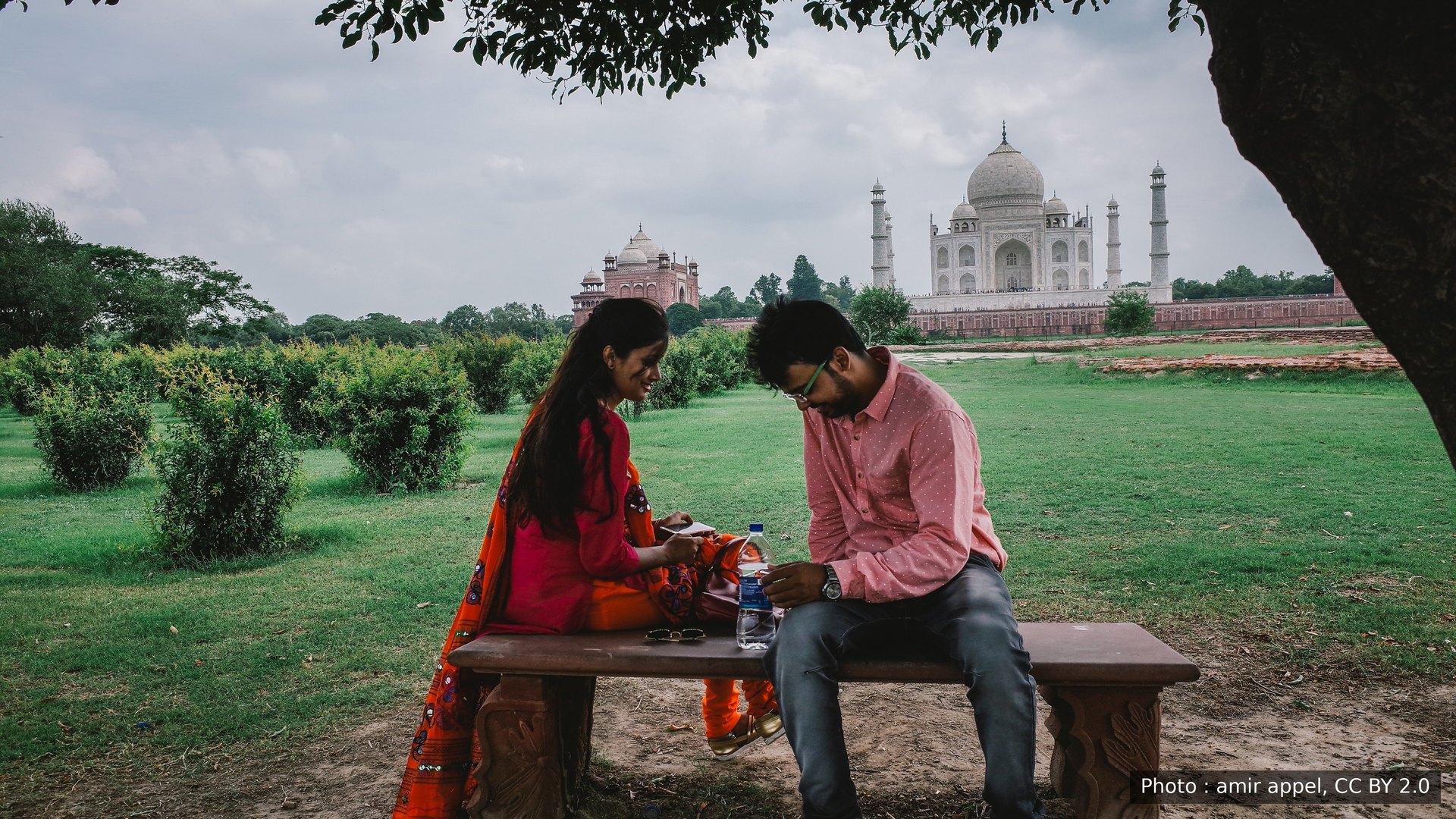 Un jeune couple sur un banc, dans les jardins face au Taj Mahal