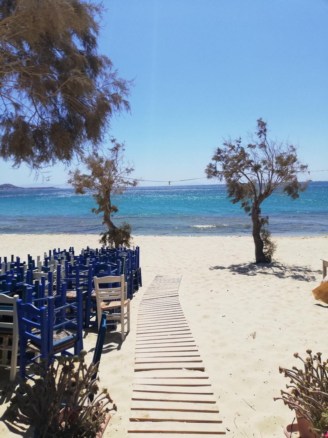 Le chemin de planches vers la plage de Plaka, entre les tables de la taverne