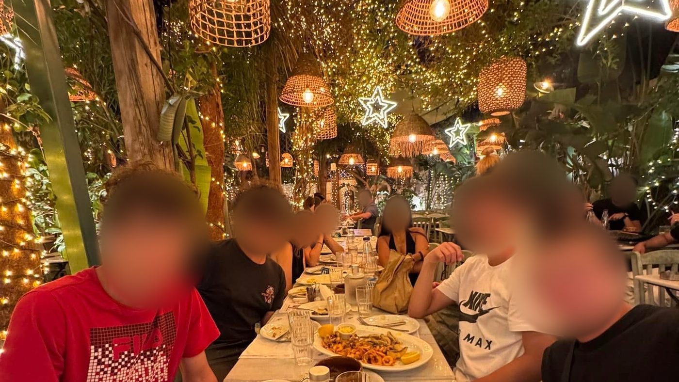Dîner tous ensemble dans une taverne illuminée de guirlandes, à Athènes